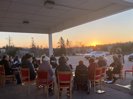 People sitting outside with the sun rising over the horizon.